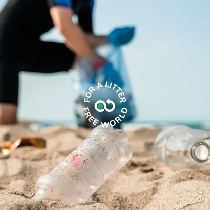 Volunteer cleaning littered beach with plastic bottle in foreground, representing NGO cleanup tracking efforts Volunteer cleaning littered beach with plastic bottle in foreground, representing NGO cleanup tracking efforts