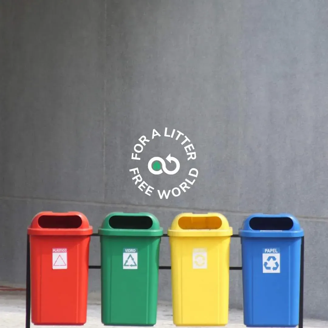 Four recycling bins in front of a wall with a circular logo reading 'FOR A LITER FREE WORLD'. Four recycling bins in front of a wall with a circular logo reading 'FOR A LITER FREE WORLD'.