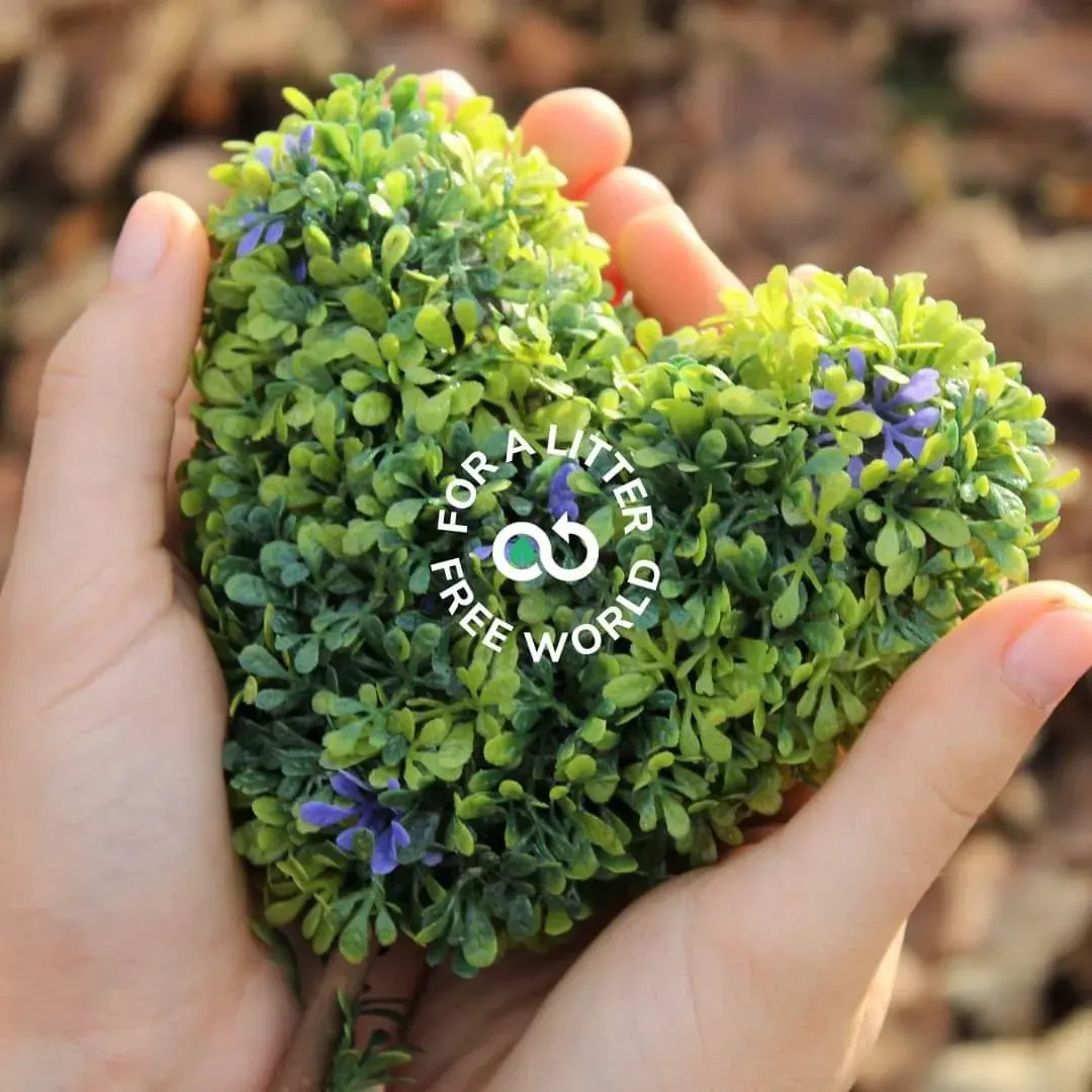 Hands holding a small shrub with a circular logo reading “FOR A LITER FREE WORLD”, symbolizing ZeLoop’s support for people who care about reducing waste